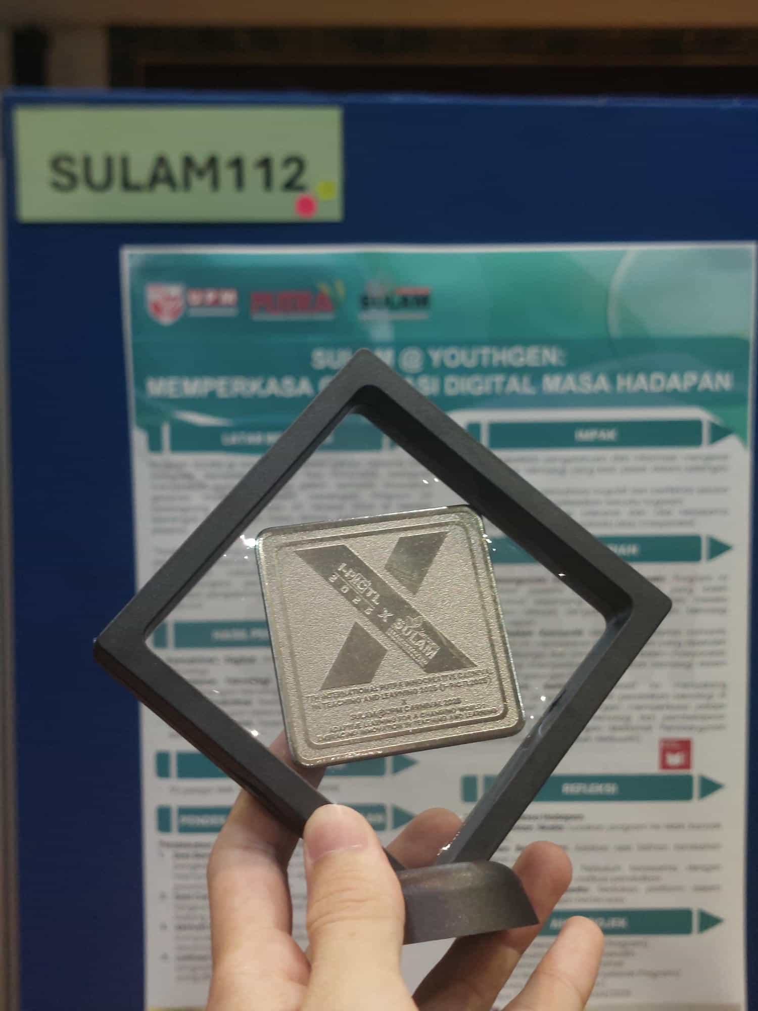 A silver medal with the academic poster in the background